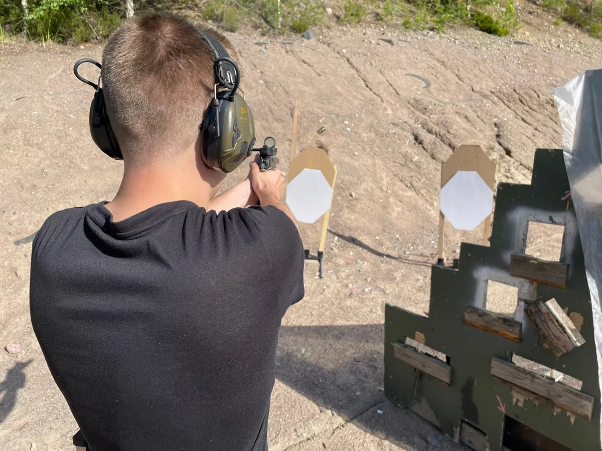 Ampuja tähtää pistoolilla ulkoradalla practical-harjoituksessa.